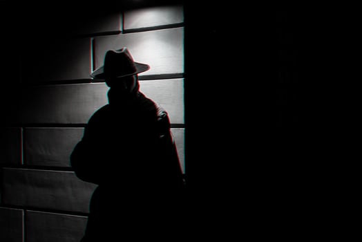 dark silhouette of a man in a raincoat with a hat at night photo