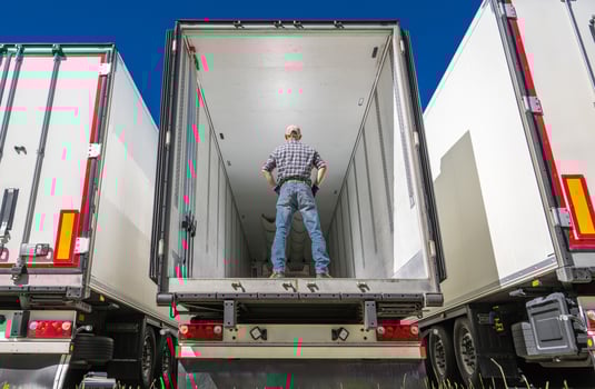 Driver standing inside of an empty semi truck trailer photo