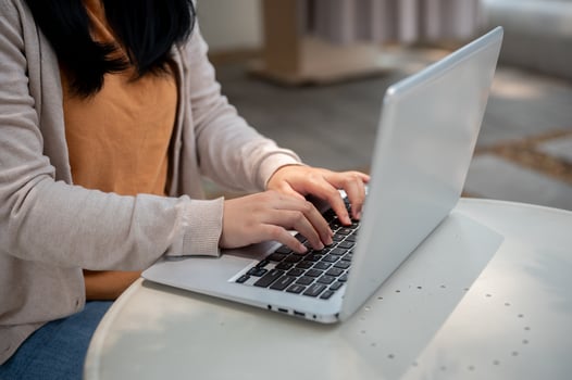 A cropped image of a woman types on her laptop keyboard, and works remotely at an outdoor table. photo