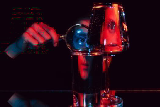 surreal portrait of a man looking through a magnifying glass and glass glasses with water photo
