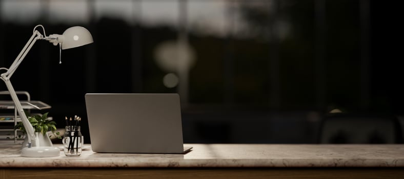 A laptop computer on a marble table in a modern dark office at night. photo