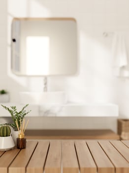 A space for showcasing products on a wooden table in a modern, luxurious white bathroom. photo