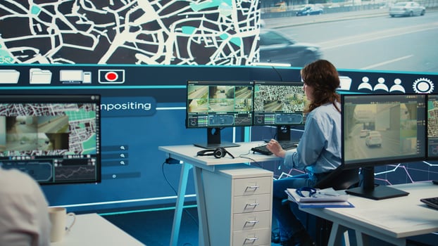 Monitoring room operator looking for routes on surveillance footage and gps satellite map, guiding courier to avoid traffic. Woman agency employee operating with CCTV system. Camera B. photo