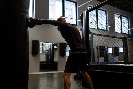 Man in boxing gloves training with heavy bag in gym photo