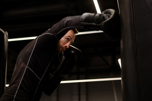 Concentrated boxer practicing punches on heavy bag in gym photo