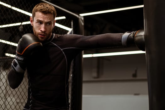 Concentrated boxer honing punching skills on heavy bag in gym photo