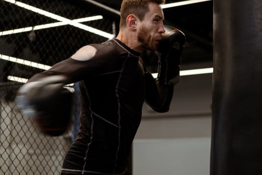 Determined boxer throwing right hook at heavy bag at gym photo