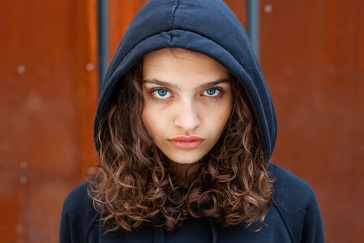 White brunette teenage girl with curly hair poses on the street in the city. photo