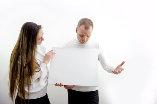 Young happy couple portrait of a confident businessman showing presentation, pointing paper placard gray background. Ideal for banners, registration forms, presentation, landings, presenting concept. photo