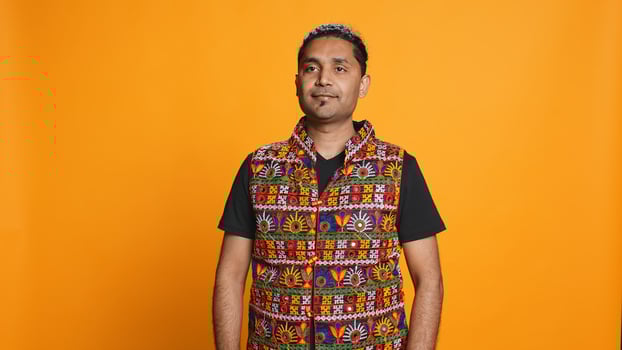 Portrait of jolly indian man with colorful garment smiling, looking pleased, isolated over studio background. Joyous person in traditional attire feeling carefree, camera B photo