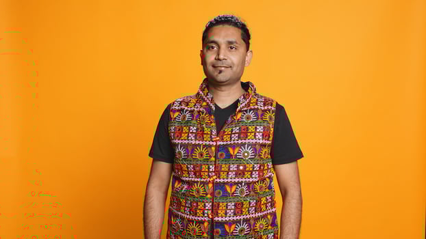 Portrait of cheerful friendly indian man smiling, looking pleased, isolated over studio background. Happy expressive asian person in traditional attire grinning, feeling satisfied, camera B photo
