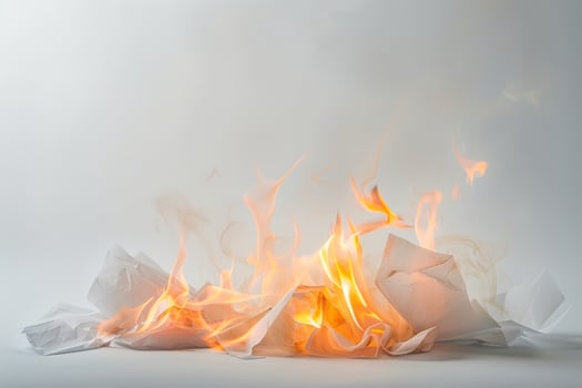 Burning paper engulfed in flames against a soft transparent white background, symbolizing destruction and transformation photo