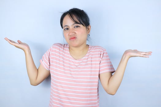 I don't know. Unsure asian woman shrugging shoulders over white studio background photo
