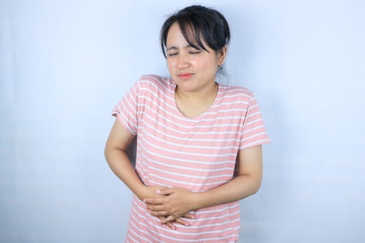 expression of young asian woman feeling menstrual pain while hand on stomach photo