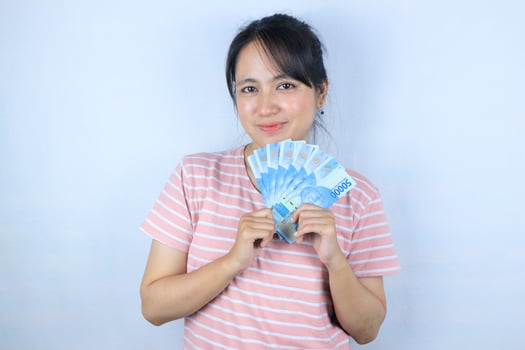 Portrait of a young asian woman holding cash money bills smiling on white background photo
