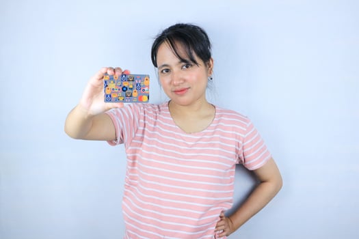 Smiling face expression of beautiful asian young woman showing credit card on white background photo