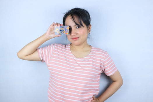 Smiling face expression of beautiful asian young woman showing credit card on white background photo