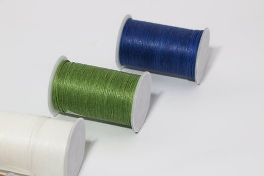 Spool of sewing thread, isolated on white background. Colored yarns used by factories in the clothing industry. Threads wound on the spool. Colored reels photo