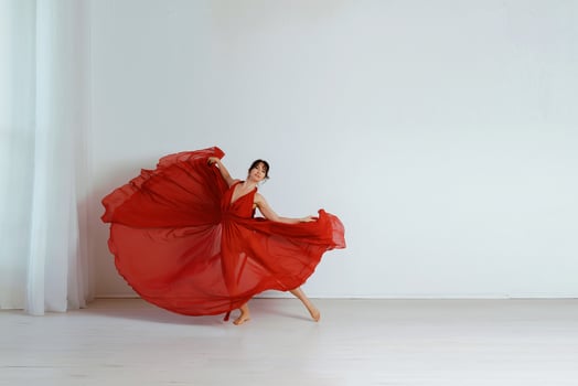 Dancer in a red flying dress. Woman ballerina dancing on a white studio background photo