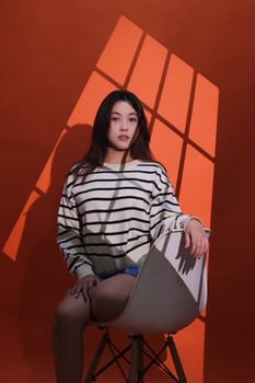 A beautiful asian girl in a dark studio, light shines on her through the curtains, forming a window pattern. Portrait of woman in projection light spotlight in studio photo