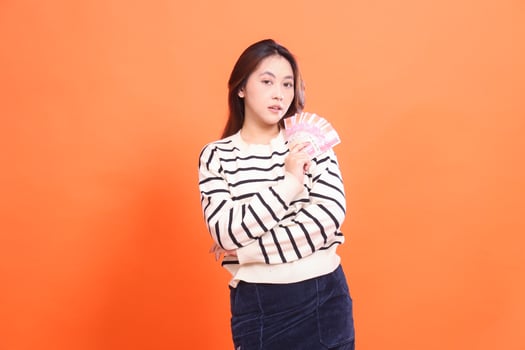 The expression of an elegant indonesia woman standing while holding some rupiah money for trading. for fashion, business and finance concept photo