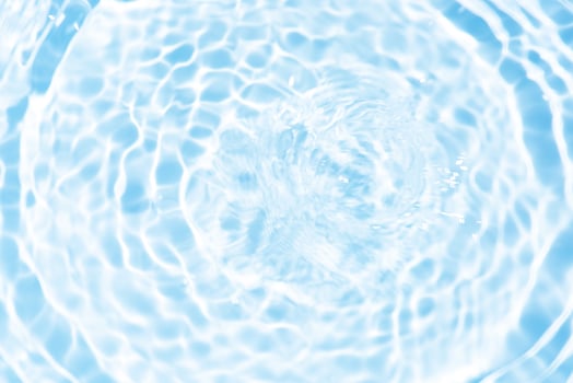 Bluewater waves on the surface ripples blurred. Defocus blurred transparent blue colored clear calm water surface texture with splash and bubbles. Water waves with shining pattern texture background. photo