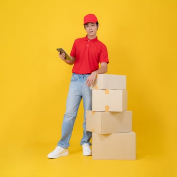Delivery man with digital tablet and parcels on yellow background photo