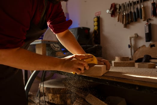 Woodworking expert using manual sandpaper to sander lumber block, making wooden products in assembling shop. Cabinetmaker polishing wood with abrasive material, spreading dust photo