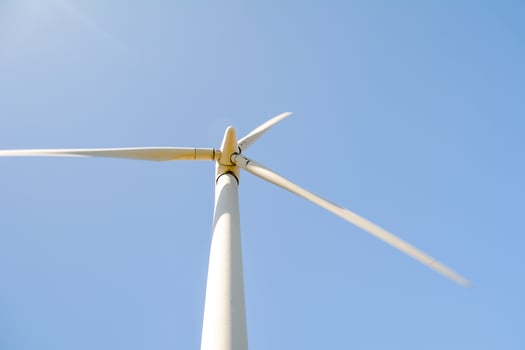 Close-up and low angle view of spinning blades of a wind turbine generating renewable energy photo
