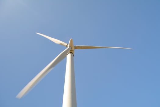 Close-up and low angle view of spinning blades of a wind turbine generating renewable energy photo