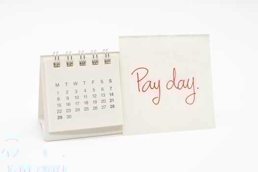 For payday concept. Desk calendar and paper note in isolated background. Business, finance, savings money, wages, payroll or accounting concept. photo
