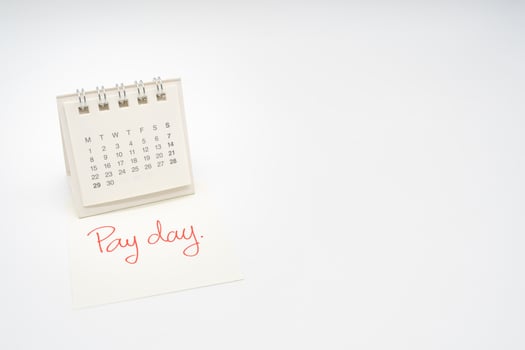 For payday concept. Desk calendar and paper note in isolated background. Business, finance, savings money, wages, payroll or accounting concept. photo