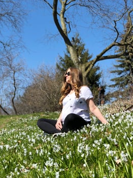 A healthy pregnant Woman is doing yoga in the Park surrounded by Beautiful snowdrops and Green grass photo