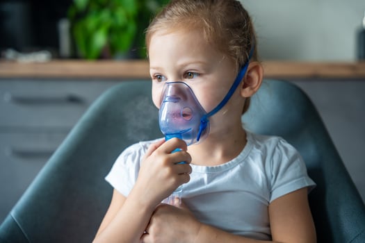 Cute little girl are sitting and holding a nebulizer mask leaning against the face, airway treatment concept photo