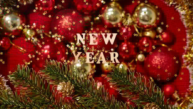 Christmas flatley with New Year lettering on blurred red gold background baubles decoration. Close-up, shiny composition. Postcard photo