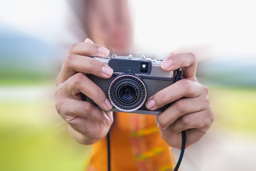 young photographer holds vintage style film camera in her hand and inspects film camera for use after film cameras have become popular with photographers today because of their unique image tones. photo