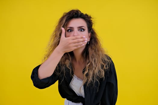 Close-up portrait of a beautiful girl on a yellow background. woman shows surprise. Shocked surprised stunned. positive human emotions photo