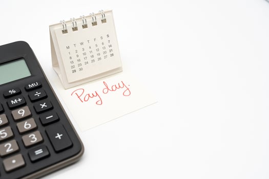 For payday concept. Desk calendar, calculator and paper note in isolated background. Business, finance, savings money, wages, payroll or accounting concept. photo