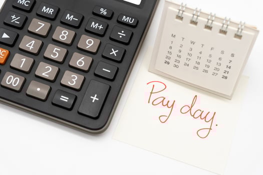 For payday concept. Desk calendar, calculator and paper note in isolated background. Business, finance, savings money, wages, payroll or accounting concept. photo