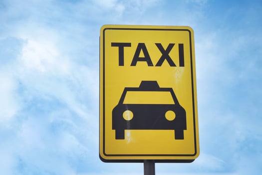 Close-up photo of a yellow Taxi stand sign attached to a metal pole