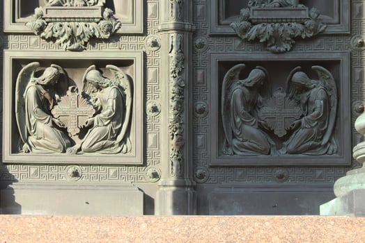 The lower part of the Isaac Cathedral door is decorated with figures of angels bent near the cross. photo