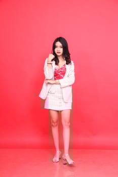 Full body portrait of young Asian Indonesian woman posing as a model wearing a cream-colored blazer. Isolated red background for content materials, banners, advertising. photo
