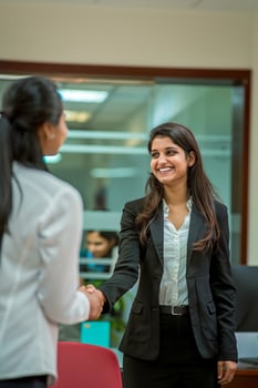 A happy young Indian woman rejoicing and shaking hands with an employee when was recruited during an interview in the office photo