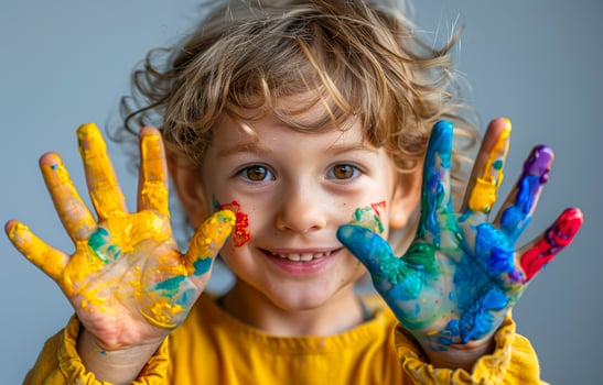 Child shows their hands covered in paint. Happy child holding up colorful painted hands photo