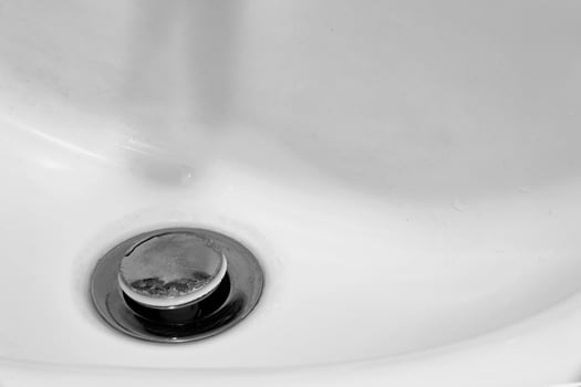 Detail of a ceramic white sink in a modern bathroom with chrome plated drain. Horizontal. For text. photo