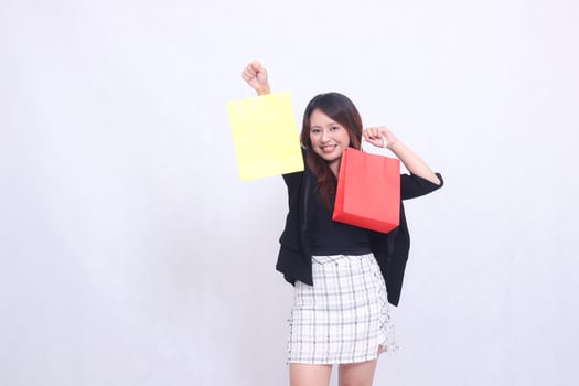 beautiful customer asian woman 20s formal office elegant happy laughing get discount shopping tote bottom top colorful paper bag goods in the middle isolated white background photo