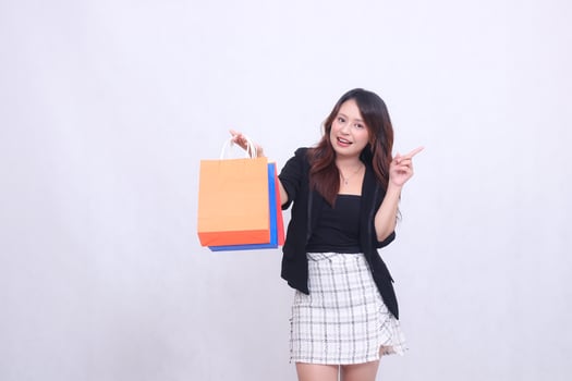 beautiful female customer asian 20s formal office cheerful get discount shopping tote paper bag aside hand gesture pointing left up isolated white background photo