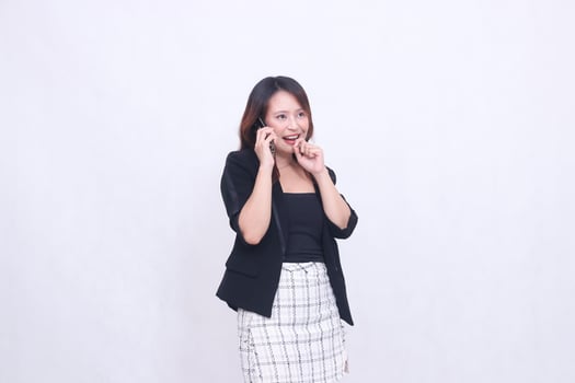 the charm of a beautiful Asian office woman in her 20s, cheerful expression, making a phone call on a cellphone while holding inspiration, isolated on a white background photo