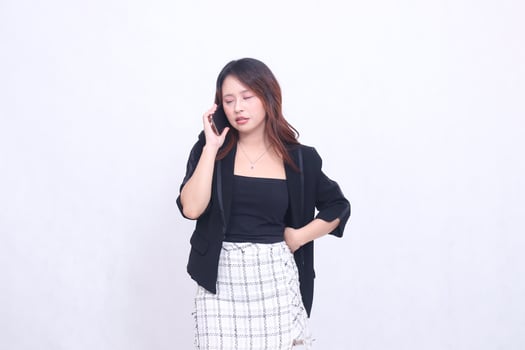 beautiful Indonesian office woman in her 20s, sleepy expression on the phone with her cellphone gadget, cream color for promo, isolated on white background photo