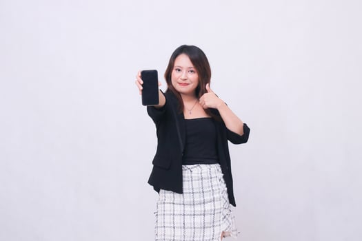 beautiful Indonesian woman in office 20s smile expression promotion cellphone gadget screen forward for promo while hand thumbs up okay cool isolated white background photo